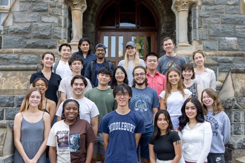 group of scholars standing in front of stone building 