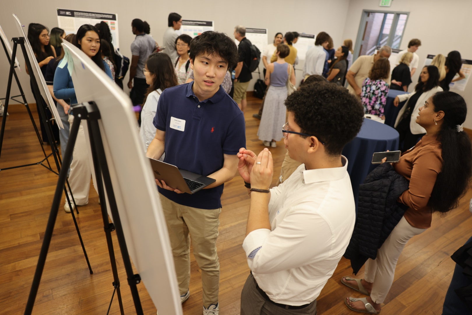 MDI Scholars talk in front of a poster at the research showcase